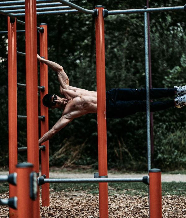 Man performing a controlled bodyweight exercise in a dark, minimalist gym.