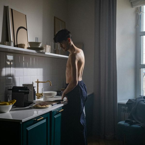 Man stretching near a window in a modern apartment early in the morning.